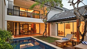 Ein modernes, zweistöckiges Haus mit Swimmingpool, Sitzgelegenheit im Freien und einem Balkon.
