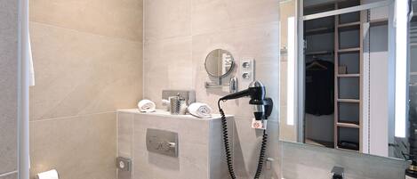 Un baño moderno con ducha, lavamanos, espejo y toallero.