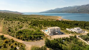 A coastal property with modern architecture, a swimming pool, and a view of the sea and mountains. - Villa Malusy ZadarVillas (Rovanjska)