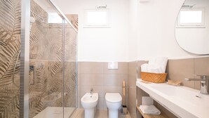 A modern bathroom with a glass shower enclosure, a bidet, a toilet, a sink with a mirror, and a towel rack. - Ciuri' affittacamere (Alcamo)