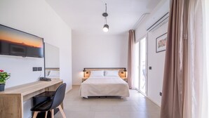 A modern hotel room with a bed, a desk with a chair, a television, and a window with curtains. - Ciuri' affittacamere (Alcamo)