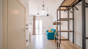 A modern living room with a sofa, a wooden bench, and a metal shelving unit. - Ciuri' affittacamere (Alcamo)