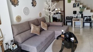 A living room with a grey sofa, decorative wall art, a round coffee table, and a staircase in the background. - Sun And Ocean House With 2 Bathrooms (Alcobaça)