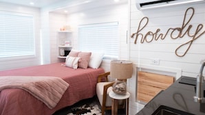 Une chambre à coucher avec un lit, une table de chevet, une lampe et un mur sur lequel est écrit le mot « howdy ».