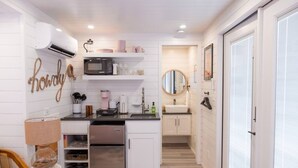 Une cuisine compacte avec des meubles blancs, un four à micro-ondes encastré et un petit plan de travail.