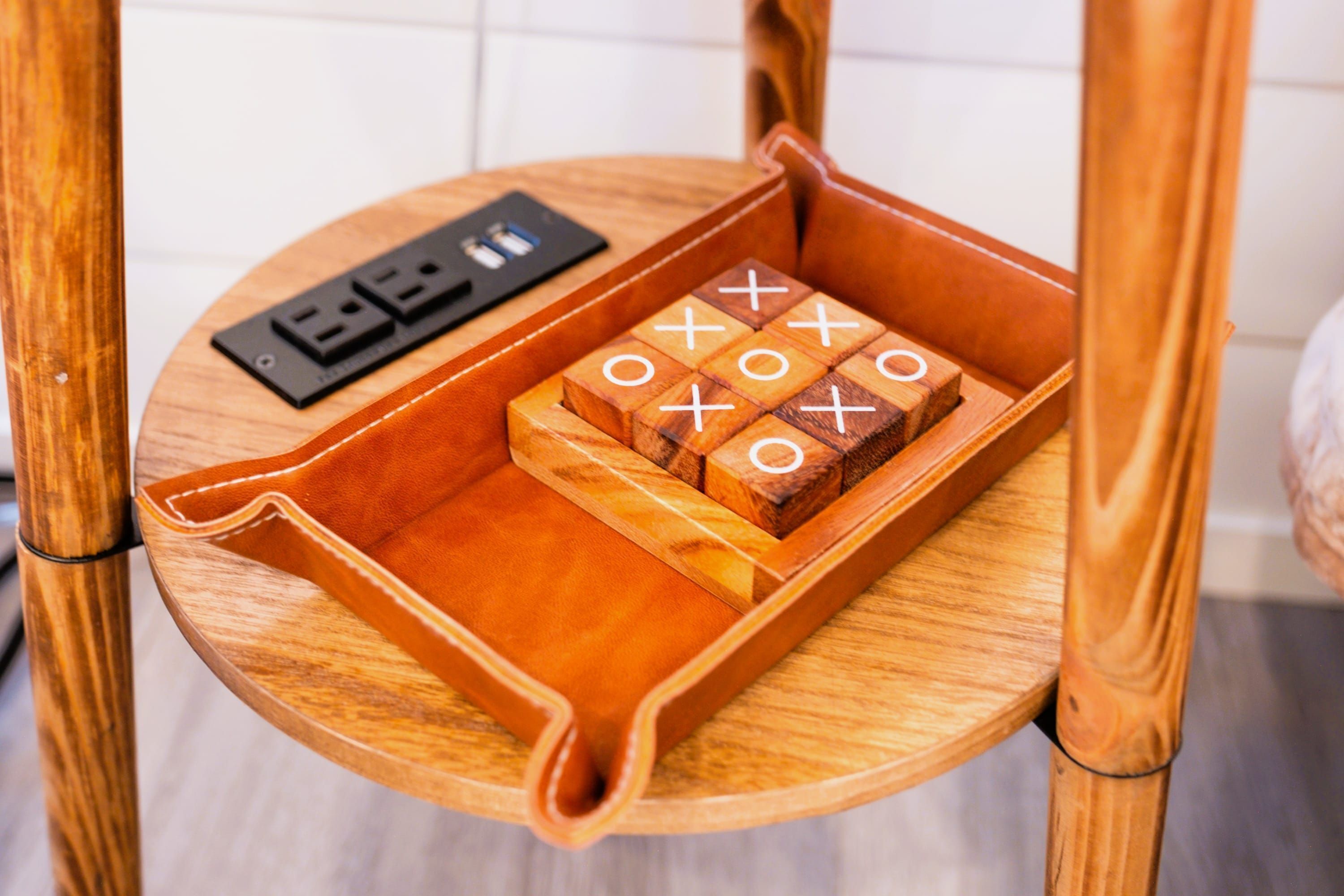 A wooden chair with a tray containing wooden blocks with symbols and a power strip.