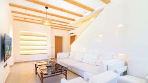 A modern living room with a white sofa, a wooden coffee table, and a ceiling with exposed beams. - Vila Fenč (Primosten)