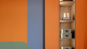 A modern living room with a sofa, a built-in wooden shelf with storage boxes, and a colorful wall design. - Playful Bright 1BR Near The Faculty of Law (Bucharest)