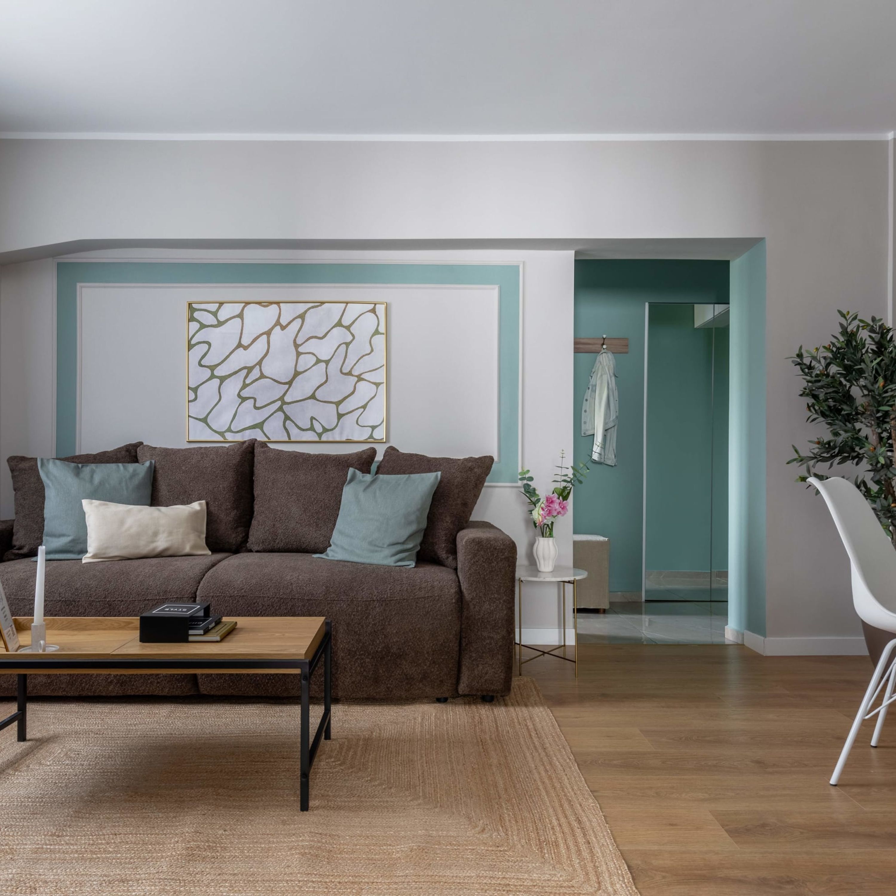 Ein modernes Wohnzimmer mit einem braunen Sofa, einem Couchtisch und einer Wanddekoration.