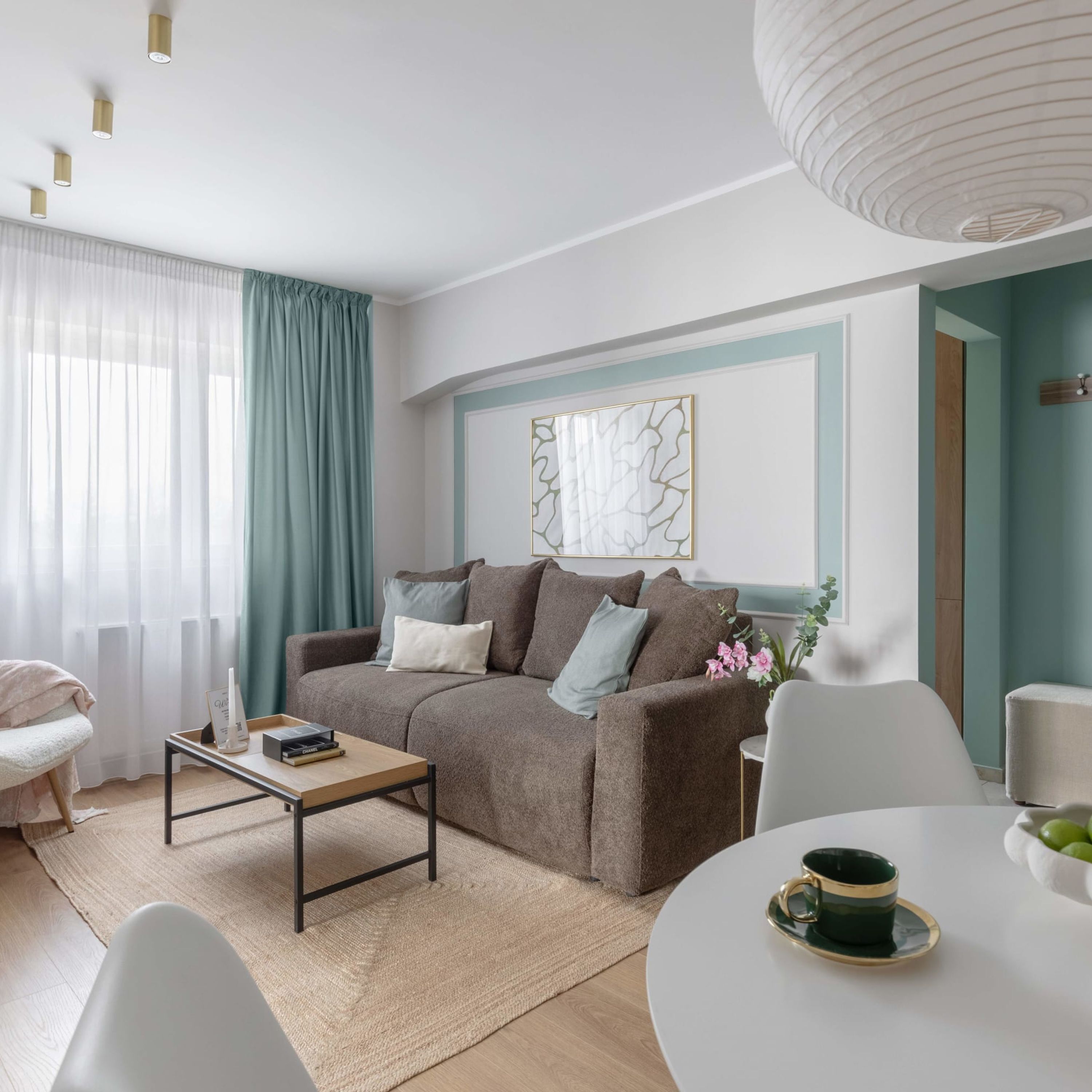 A modern living room with a sofa, coffee table, and a dining area with a table and chairs.