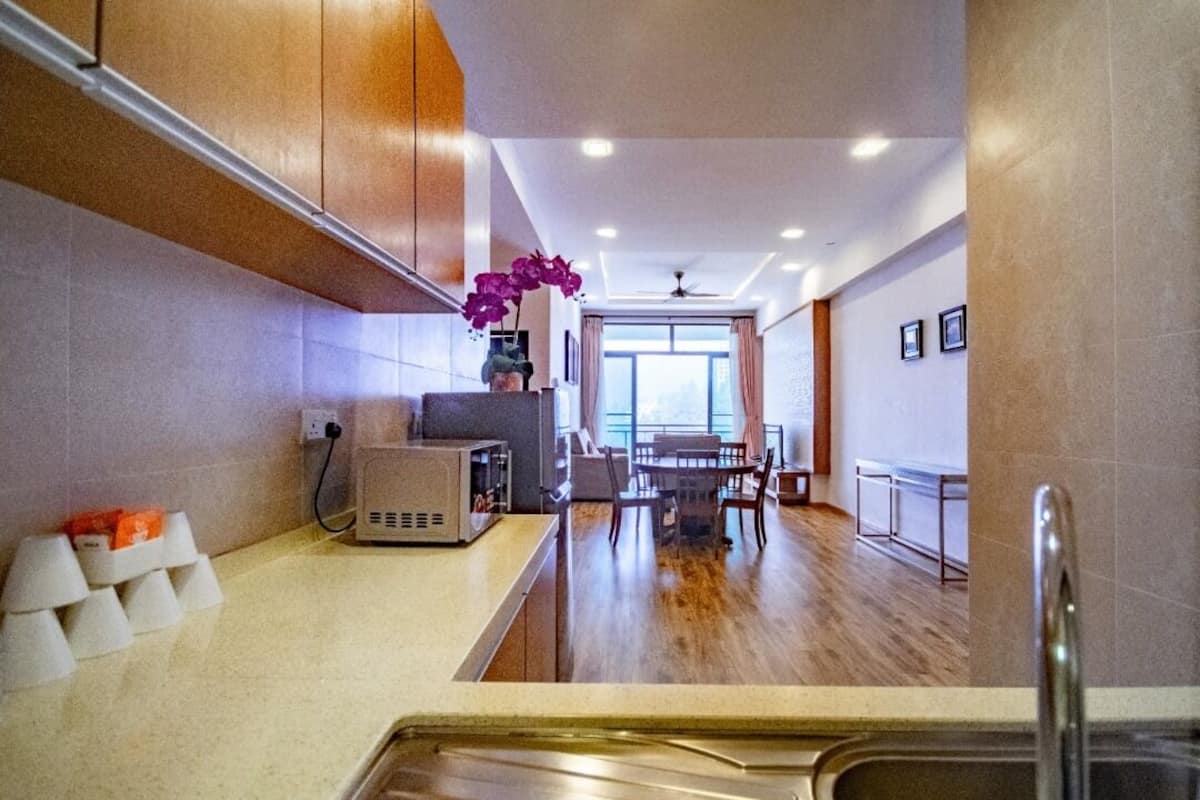 A modern kitchen with wooden cabinets, a central island, and a dining area with a table and chairs.
