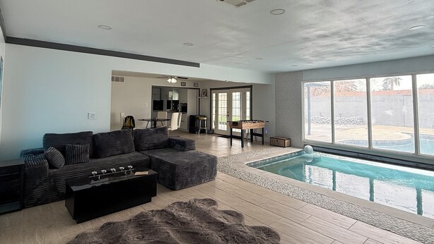 Ein geräumiges Wohnzimmer mit einer großen Eckcouch, einem Couchtisch und einem Poolbereich mit Blick ins Freie.