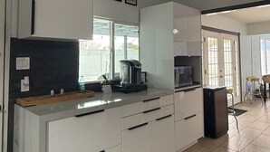 Eine moderne Küche mit weißen Schränken, einer integrierten Kaffeemaschine und einem großen Fenster.