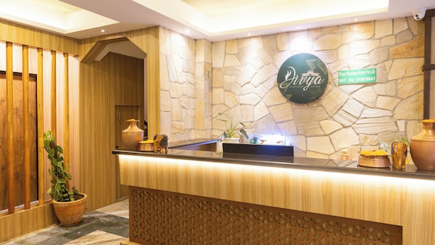 A reception area with a stone wall, a wooden reception desk, and a potted plant. - Divya Boutique Inn (Kathmandu)