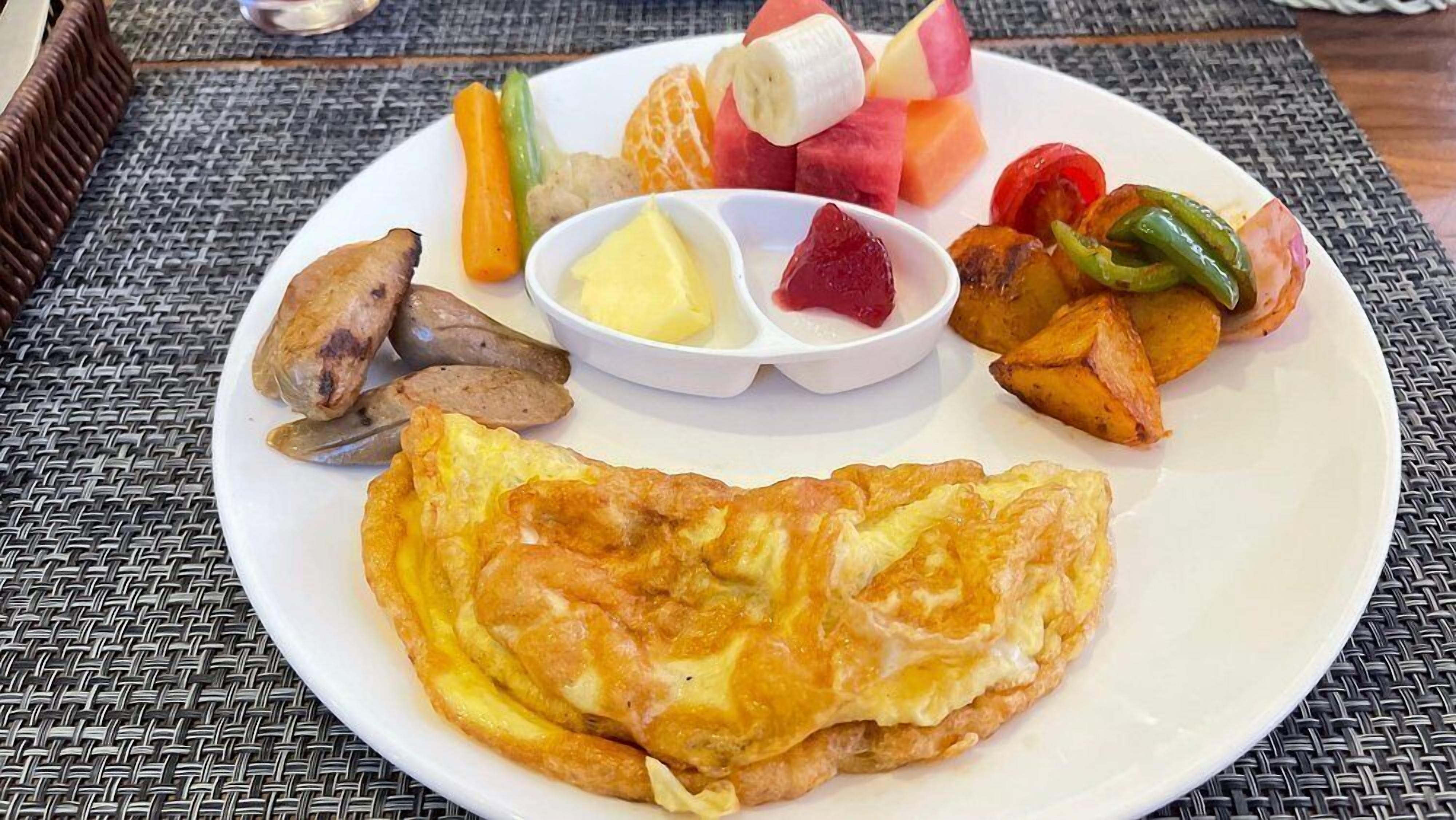 Un plato con tortilla, patatas asadas, verduras a la parrilla y rodajas de fruta.