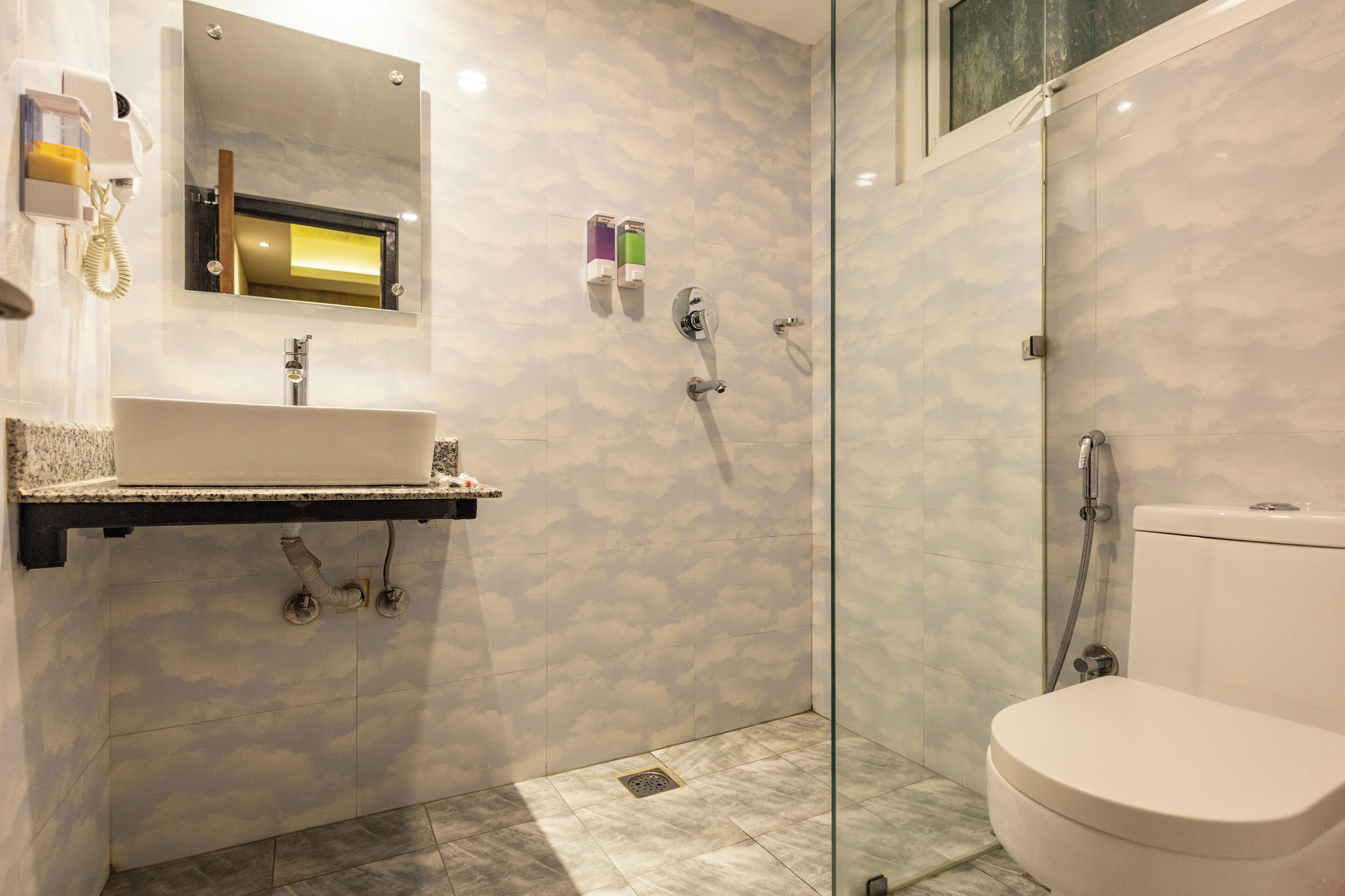 Um banheiro moderno com toucador de mármore, box de vidro e vaso sanitário.