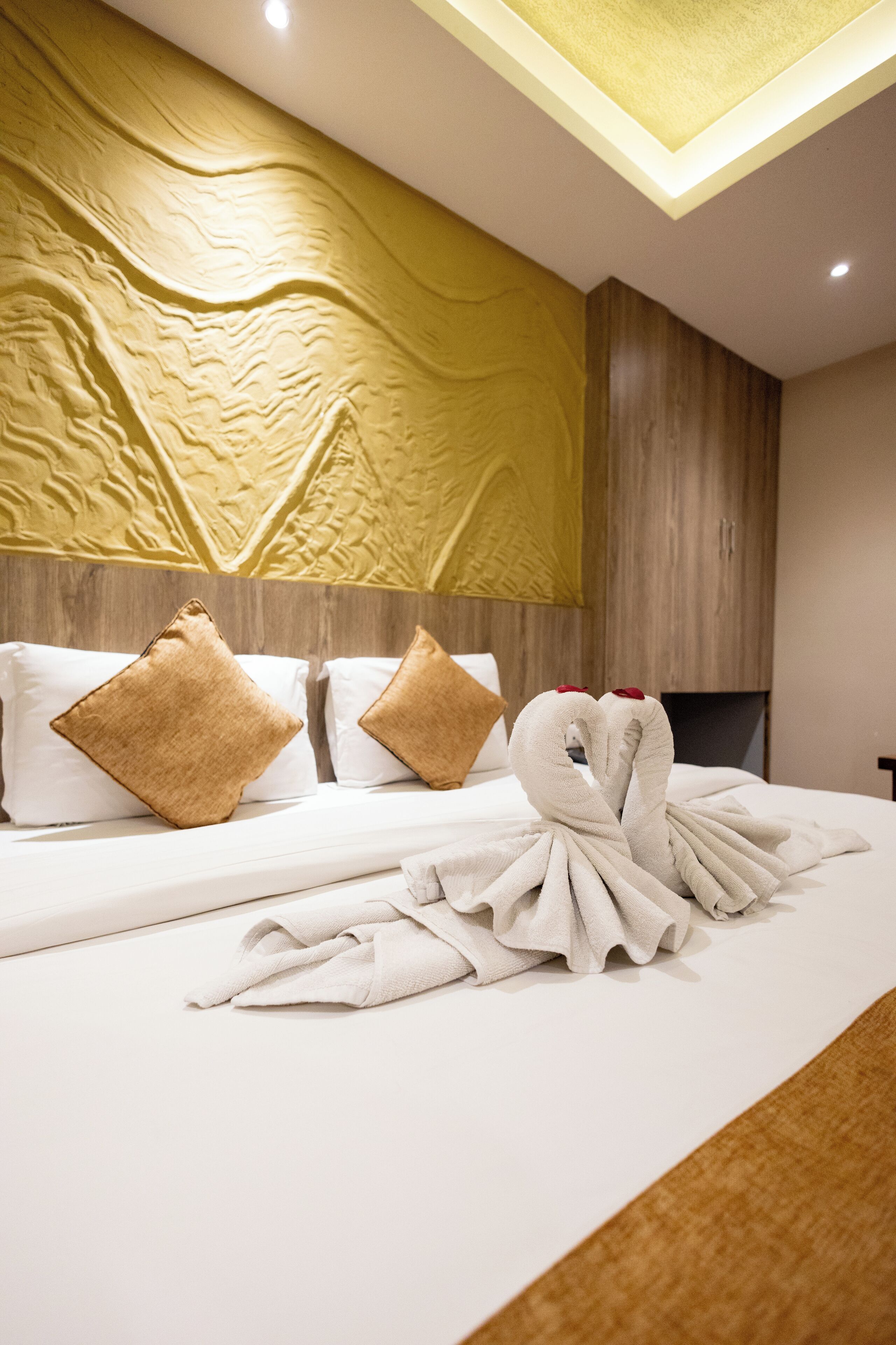 A hotel room with a bed, pillows, and a towel art installation.