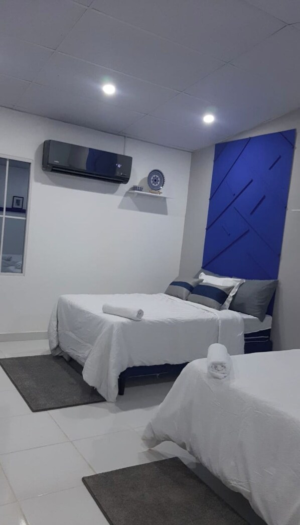 A modern hotel room with two beds, a flat-screen TV, and a decorative wall panel.