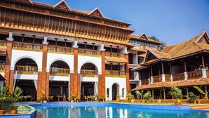 Ein Resort mit großem Pool, mehreren Balkonen und traditioneller Architektur.