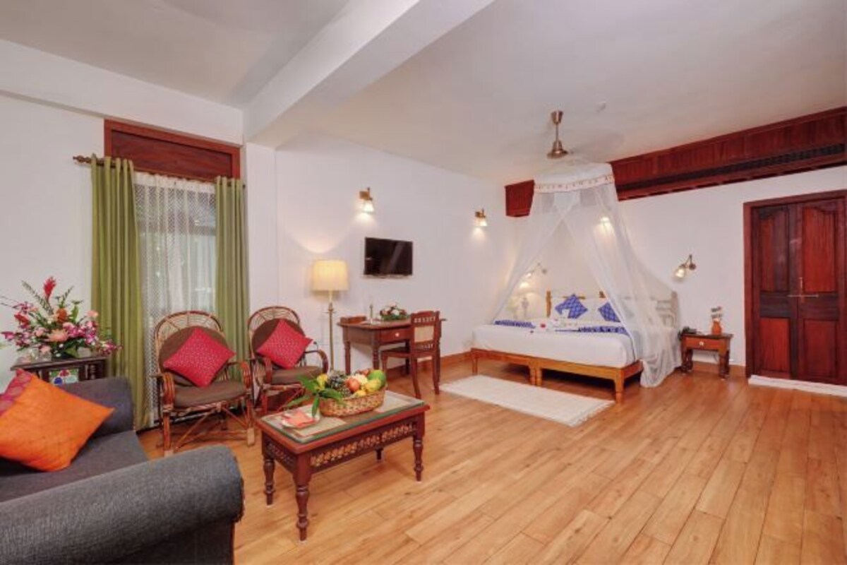 A room with a bed, a sofa, a table with fruit, and a TV.