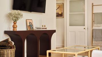 A living room with a dark brown console table, a glass coffee table, a TV mounted on the wall, and a white door with frosted glass panels.