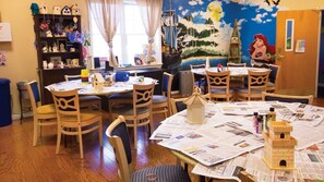 Cozy room with a central table, colorful mural, and bookshelf.