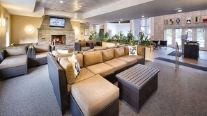Eine geräumige Innenlounge mit Kamin aus Stein, bequemen Sitzgelegenheiten und einem Flachbildfernseher.