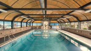 Une piscine intérieure avec vue sur la plage, grâce à de grandes baies vitrées.