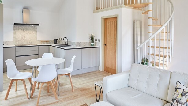 A modern kitchen with white cabinets, a marble countertop, and a white dining set. - Host Stay Sunshine Cottage (Leyburn)