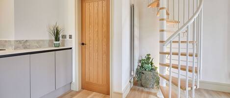 A modern kitchen with a wooden door, white cabinets, and a marble countertop.