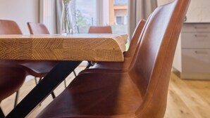 A dining table with a wooden top and a chair with a leather seat.