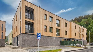 A modern building with a wooden facade, a stone base, and a parking sign.