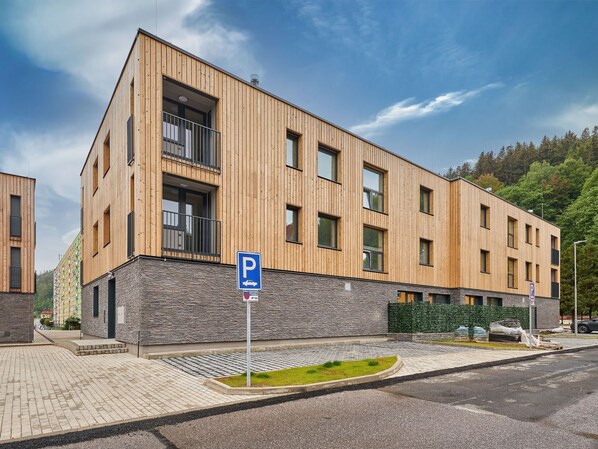 A modern building with a wooden facade, a stone base, and a parking sign.