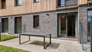 A modern building with a stone facade, large windows, and a metal table in the outdoor area.