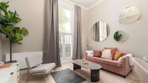 Ein modernes Wohnzimmer mit einer Couch, einem Couchtisch, einem Sessel, einer Zimmerpflanze und einer Heizung.