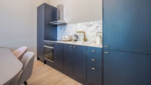 Eine moderne Küche mit dunkelblauen Schränken, einem Edelstahlbackofen, einer weißen Arbeitsplatte und einer Marmor-Spritzschutzwand.