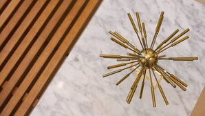 Ein moderner Kronleuchter mit Metalloptik, ein Holzlattentisch und eine Marmorplatte.