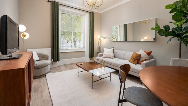 Ein modernes Wohnzimmer mit Sofa, Couchtisch und Fernseher.
