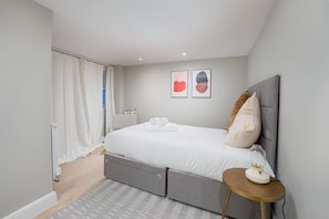 A modern bedroom with a bed, bedside table, and artwork on the wall. - Trendy Flat by Hyde Park (PS1) (Greater London)