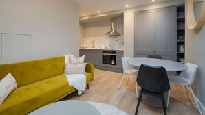 A modern kitchen with grey cabinets, a built-in oven, and a stainless steel range hood. - Trendy Flat by Hyde Park (PS1) (Greater London)