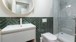 A bathroom with a sink, toilet, and shower. - Trendy Flat by Hyde Park (PS1) (Greater London)