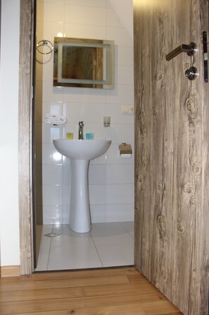 A bathroom with a white sink, a mirror, and a wooden door. - Hotel TWINS Achkhoti (Kazbegi)