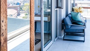A balcony with a view of the city, a sliding glass door, and a sofa with decorative pillows. - Deluxe Urban Retreat Summit on Quarter (Cape Town)