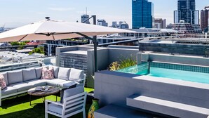 A rooftop terrace with a pool, outdoor seating, and a city skyline in the background. - Deluxe Urban Retreat Summit on Quarter (Cape Town)
