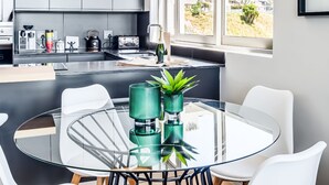 A modern kitchen with grey cabinets, a black countertop, and a large window offering a view of a hillside. - Deluxe Urban Retreat Summit on Quarter (Cape Town)