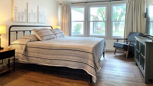 Une chambre avec un lit, un bureau, une chaise et un téléviseur.