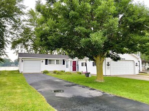 A single-story house with a garage, a driveway, and a tree in front. - Lake House | Kayaks | Patio/Deck | Private Pier (Rome City)