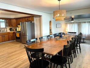 A spacious kitchen with wooden cabinets, a stainless steel refrigerator, and a dining area with a wooden table and black chairs. - Lake House | Kayaks | Patio/Deck | Private Pier (Rome City)