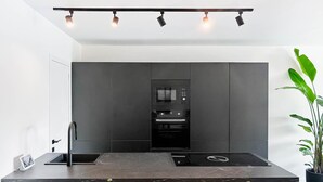 A modern kitchen with a central island, built-in appliances, and a minimalist design. - Charming Authentic Home With Garden (Borgloon)