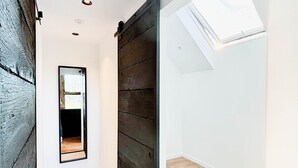 A modern interior with a wooden floor, a sliding door, and a skylight. - Charming Authentic Home With Garden (Borgloon)